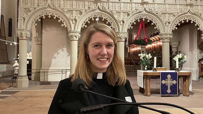 Eine Pastorin steht im weihnachtlich geschmückten Inneren des Schleswiger Doms. 