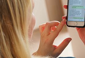 Frau mit Smartphone, auf dem WhatsApp geöffnet ist.