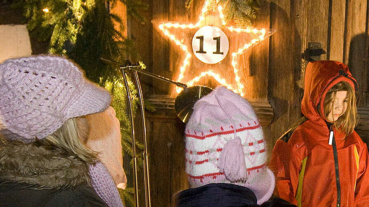 Kinder klopfen an die Tür des lebendigen Adventskalenders.