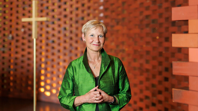 Bischöfin Kirsten Fehrs steht in grünem Gehrock im Ökumenischen Forum Hamburg