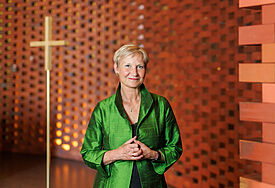 Bischöfin Kirsten Fehrs steht in grünem Gehrock im Ökumenischen Forum Hamburg