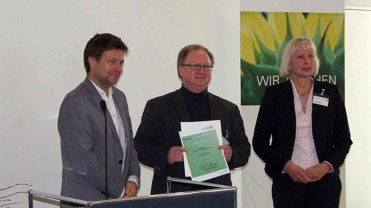Übergabe der Auszeichung (v.l.n.r.): Dr. Robert Habeck (Minister für Energiewende, Landwirtschaft, Umwelt und ländliche Räume des Landes Schleswig-Holstein), Pastor Jan Christensen (Pastor für Umweltfragen der Nordkirche), Jurymitglied Theda Freseman