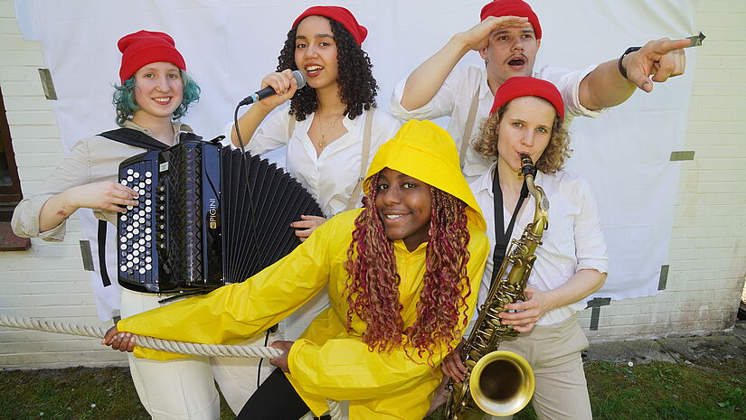 Fünf junge Leute mit Kopfbedeckiungen und Musikinstrumenten.