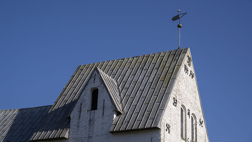 Blick auf den Turmhelm eines viereckigen, weißen Dorfkirchturms
