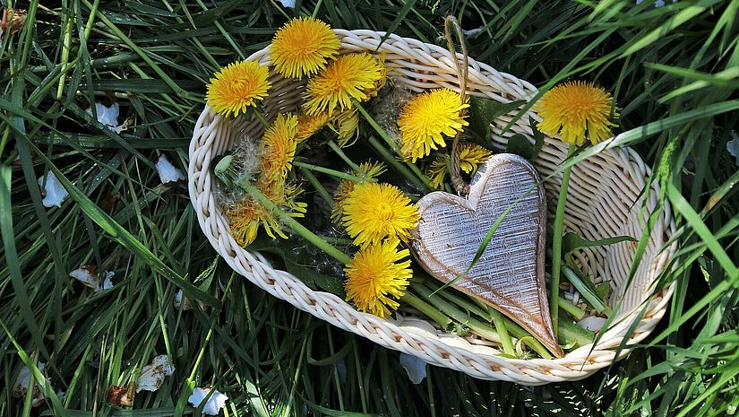 Frühlingsgefühle? Das Team von St. Moment hat ein paar Ideen, wie das Liebesfest ein Knüller wird. Korb mit Blumen und einem Holzherz