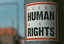Die Menschenrechte gelten für alle Menschen: "Every human has rights" steht auf einem Aufkleber an einem Laternenpfahl.