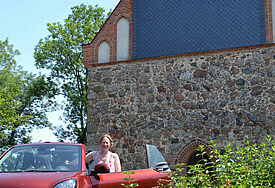 Pastorin Verena Häggberg mit dem e-Auto vor der Kirche Vipperow