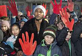 Schüler aus Berlin demonstrieren am Montag (10.02.2014) zusammen mit dem ehemaligen Kindersoldaten Michael Davies (M.) aus Sierra Leone zum "Red Hand Day" am 12. Februar vor dem Reichstag in Berlin.