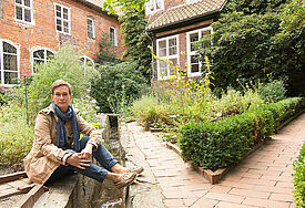 Carolin George sitzt im Kräutergarten des evangelischen Frauenklosters Lüne bei Lüneburg