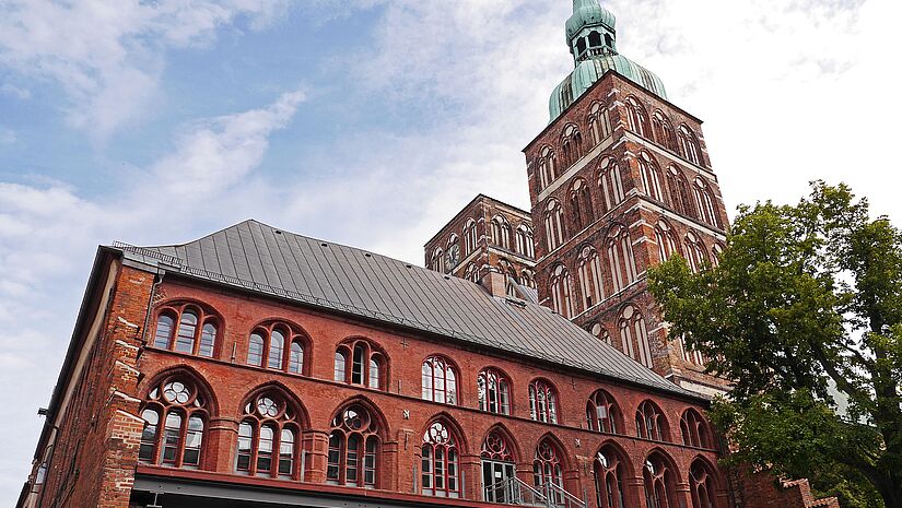 Von unten fotografiert, links das rote Rathaus, daneben ragen die Türme von St. Nikolai in den Himmel; nur der rechte Turm hat ein zwiebelförmiges Kupferdach
