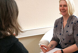 Verena Hein berät mit Block in der Hand eine andere Person, die nicht erkennbar ist