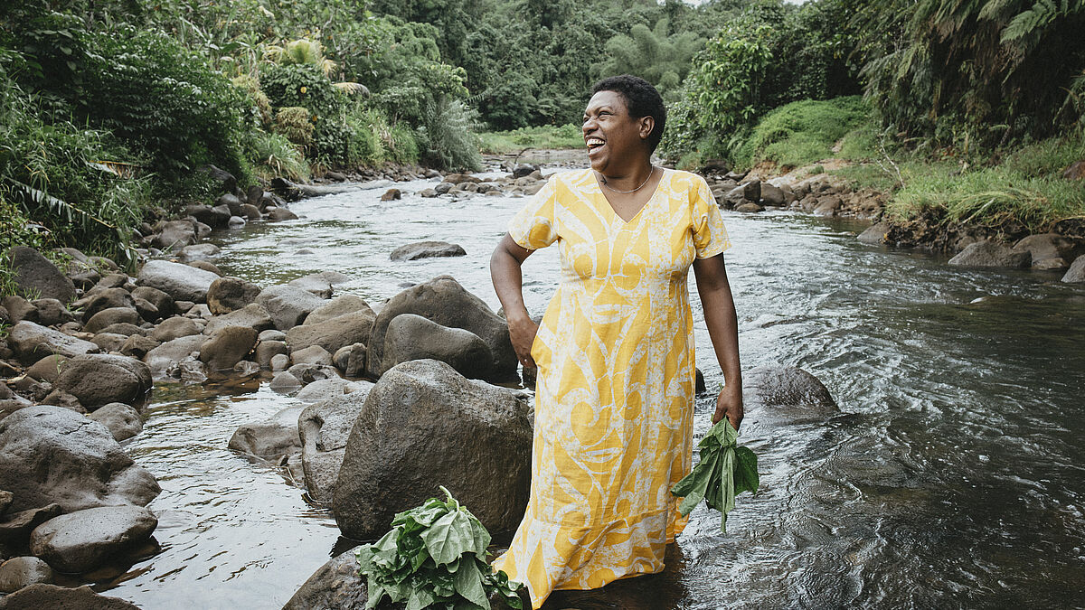 Luisa Curuki (35) Vorsitzende vom Womens‘ Club Cogea, wäscht Bele-Blätter im Fluss hinter ihrem Haus. Die Partnerorganisation von Brot für die Welt, FCOSS (Fiji Council of Social Services) unterstützt die Umsiedlung des Dorfes Cogea. Cogea wurde vom Zyklon "Yasa" Ende 2020 zerstört. FCOSS steht einer ganzen Gemeinschaft bei der Umsiedlung ihres Dorfes zur Seite – damit sie den immer häufigeren Stürmen und Überschwemmungen, dem Anstieg des Meeresspiegels trotzen kann. 