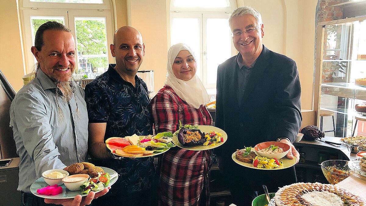 Thorsten Heise, Ayman und Nada Al Kassar sowie Jakobi-Pastor Lutz Jedeck begrüßen ihre Gäste mit vielen Leckereien (von links)