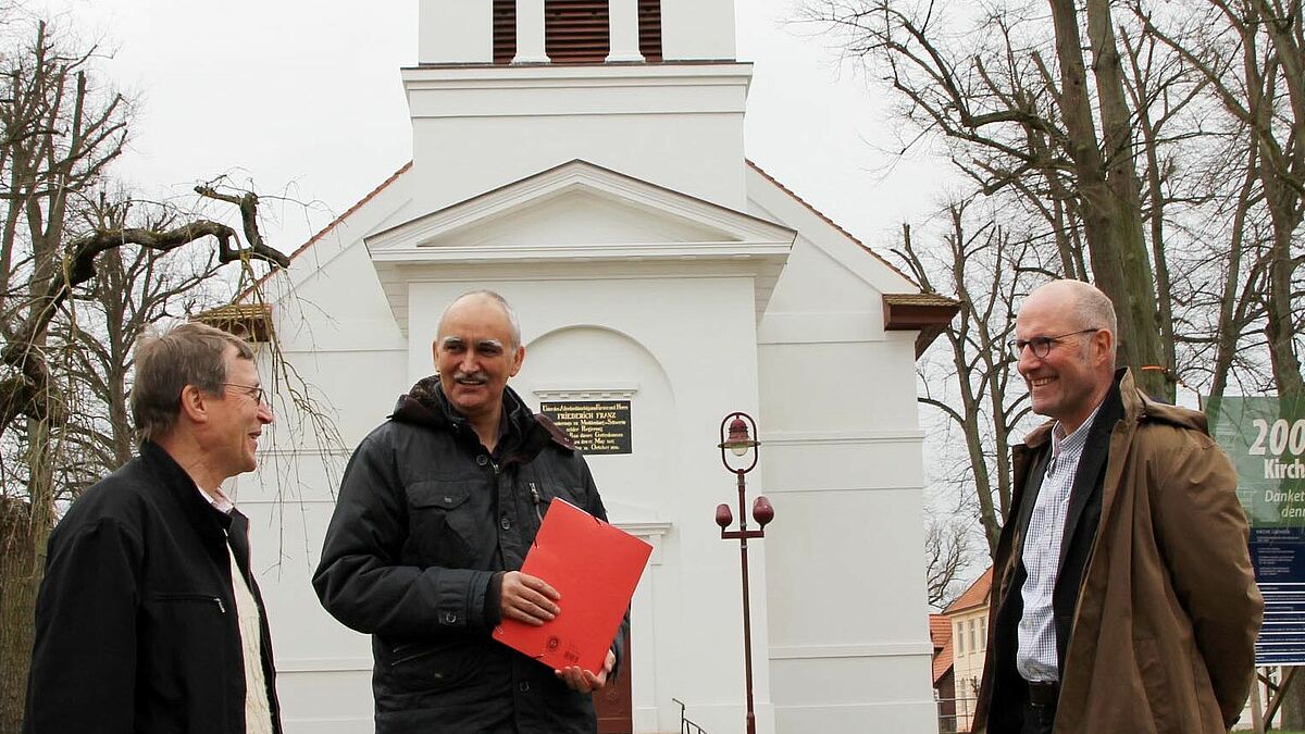 Die Lübtheener Kirche ist frisch saniert, ein Teil der Kosten wurde durch den Notfallfonds mit Lotteriegeldern abgedeckt. Pastor Markus Holmer, Fachbereichsleiter Kurt Reppenhagen (Kirchenkreisverwaltung MV) und Dr. Ait Stapelfeld, Geschäftsführer von Lotto MV, freuen sich über das Ergebnis. 