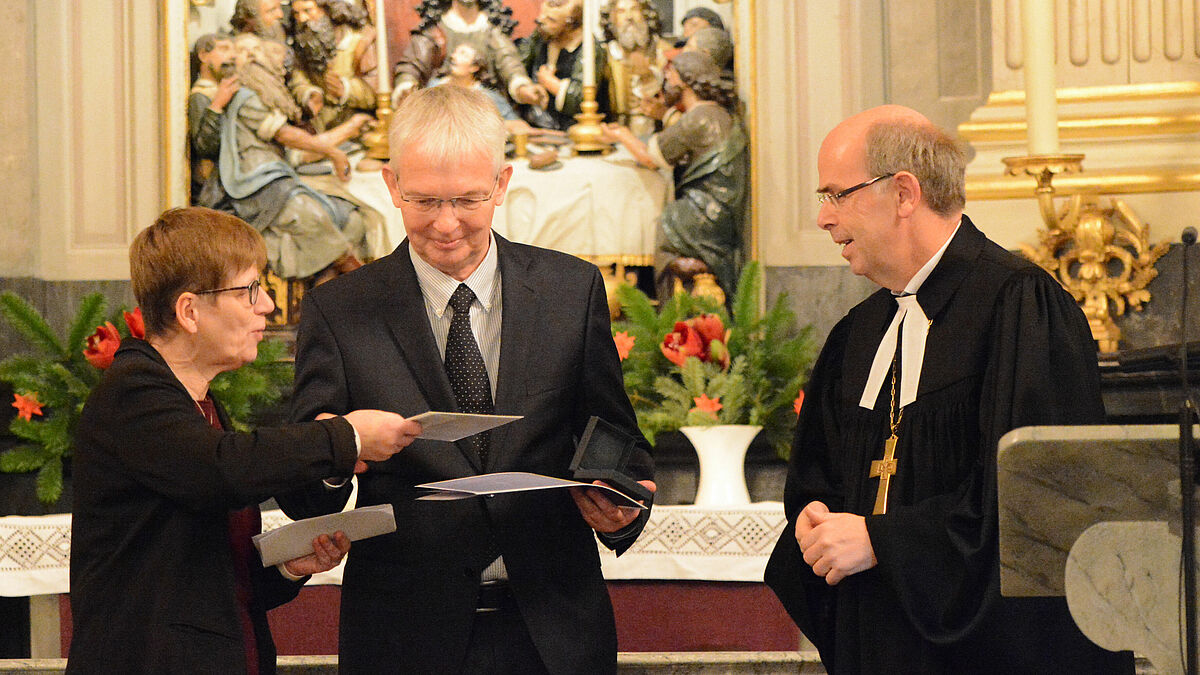 Pröpstin Johanna Lenz-Aude und Bischof Gothart Magaard (r.) gratulieren Henning Lüthke zur Bugenhagen-Medaille der Nordkirche.