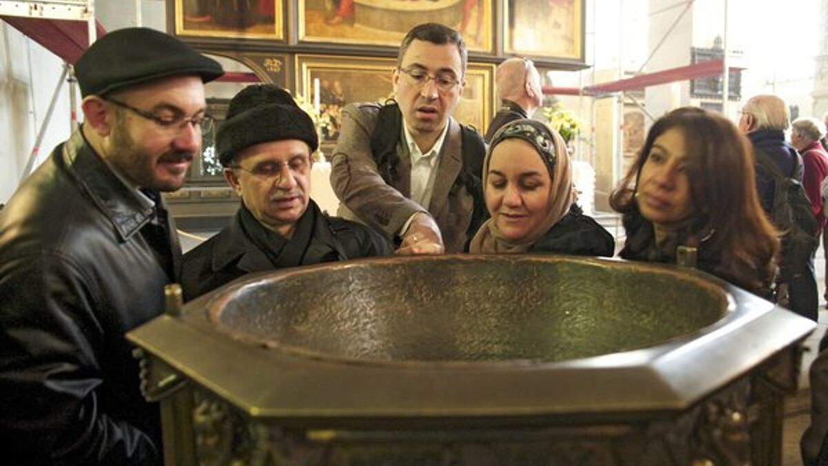 Eine Gruppe von Muslimen und Christen steht am Taufbecken in der Wittenberger Stadtkirche, der bevorzugten Predigtkirche von Martin Luther. (epd-Archiv, Symbolbild)