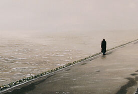 Graues gemaltes Bild von einer einsamen Person am Meer