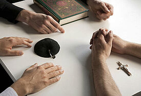 Symbole für die drei monotheistischen Weltreligionen Christentum, Judentum und Islam: Kreuz, Kipa und Koran