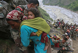 Soldaten helfen einer Frau mit Kind auf dem Rücken während der Rettungsaktion in Godvindghat im Himalaya.