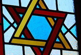 Ein bunter Davidstern in einem Synagogenfenster.