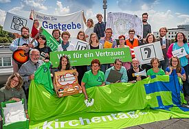 Noch genau ein Jahr bis zum Kirchentag Menschen mit grünen Bannern zum Kirchentag, die sich freuen