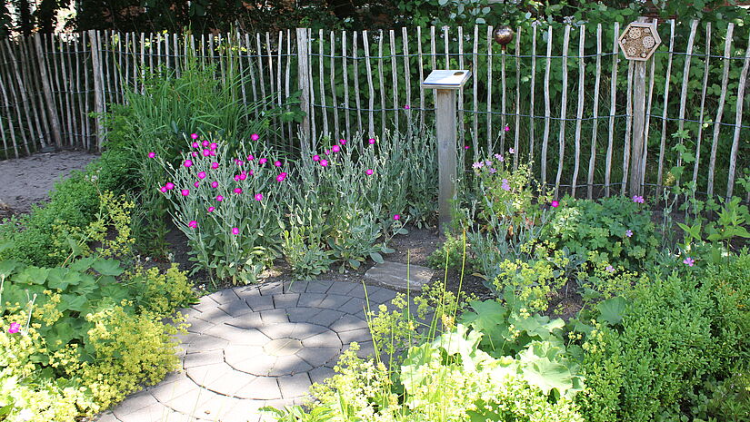 ein Platten weg führt durch ein sehr kleine Gartenanlage zur Gottesperle