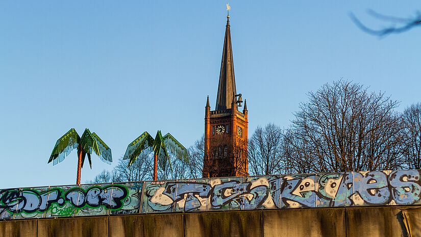 Die Kirche hinter Kunstpalmen des Park Fiction (St. Pauli).