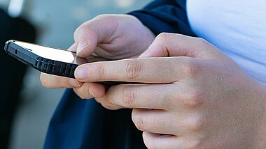 Hände halten ein Smartphone.