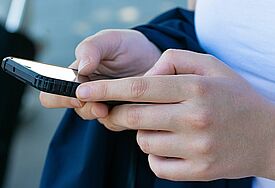 Hände halten ein Smartphone.