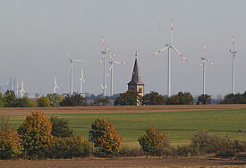 Blick auf den Kirchturm und die Windkraftanlage von Arnstedt (Sachsen-Anhalt).
