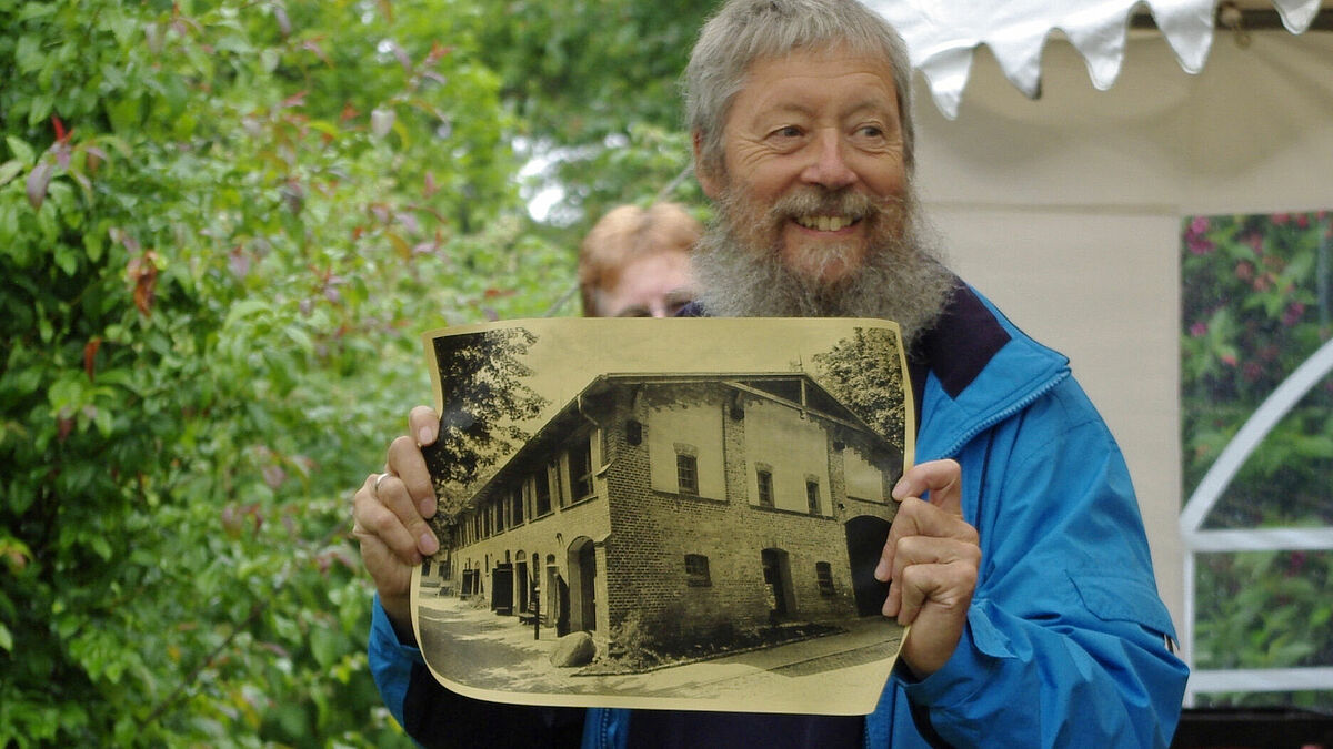 Der ehrenamtliche Bauleiter Friedrich Heilmann mit einem Bild der Scheune.