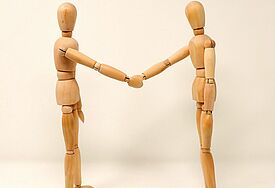 Zwei Holzfiguren reichen sich die Hand