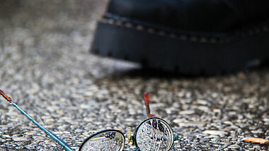 Stiefel und zerbrochene Brille als Symbol für Rechte Gewalt 