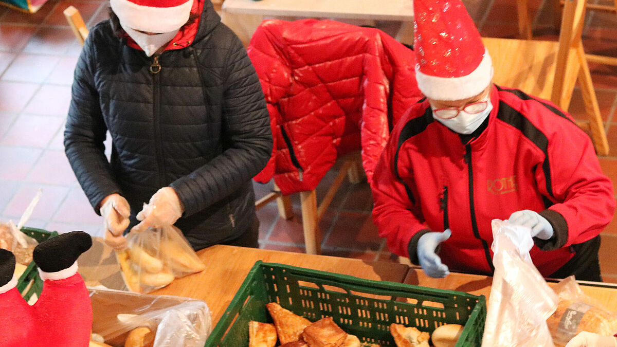 Die Ehrenamtlichen packen Brot und Brötchen in Tüten, um sie zusammen mit anderen frischen Lebensmitteln und kleinen Aufmerksamkeiten an die Wartenden auszugeben. 