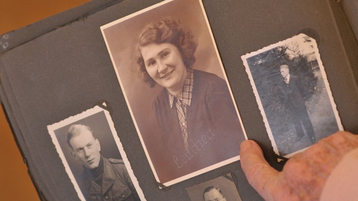 Eine Seniorin schaut sich altes Fotoalbum mit Familienfotos an. (Symbolbild)