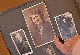 Eine Seniorin schaut sich altes Fotoalbum mit Familienfotos an. (Symbolbild)