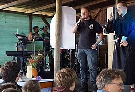 Pastor Mathias Thieme steht auf einer Bühne und spricht zu den Jugendlichen