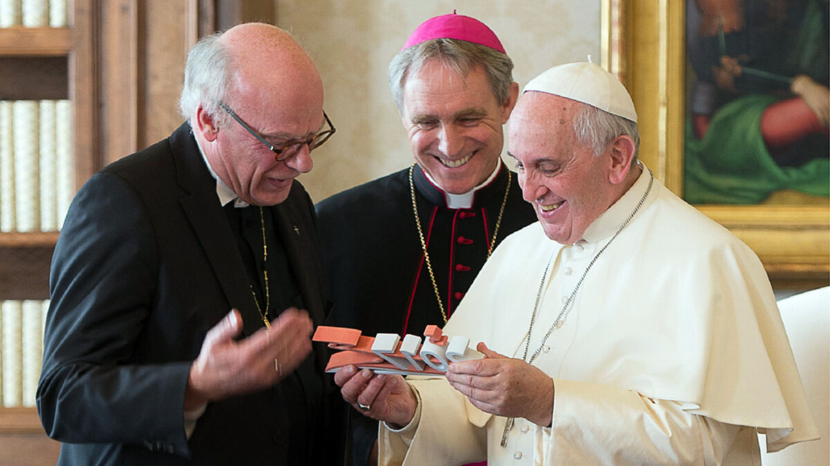 Symbolisches Geschenk: Bischof Ulrich (li.) übergibt Papst Franziskus eine Statue mit dem Logo „2017 gemeinsam unterwegs“. In der Bildmitte: Kurienerzbischof Georg Gänswein.