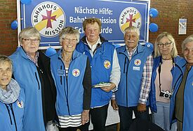 Das Team vor dem Banner der Bahnhofsmission in blauen Westen