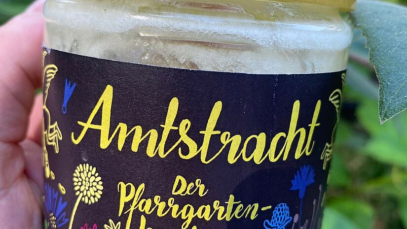 Ein Glas Amtstracht, der Pfarrgartenhonig aus Lohmen. Ein Glas Honig. Auf dem Etikett steht "Amtstracht, der Pfarrgarten-Honig".