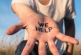 Hand mit Schriftzug "We help"