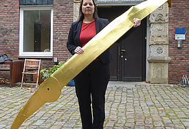 Die Hamburger Katharinen-Pastorin Maren Traumtann mit dem abgerissenen Turmuhr-Zeiger vor der Hauptkirche