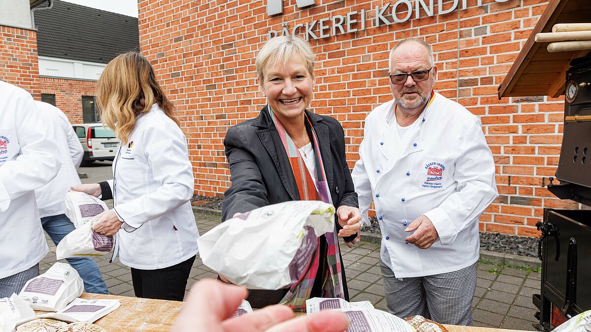 Aktion Brot und Segen, Bischöfin Fehrs reicht ein Brot zum Martinstag über den Tresen
