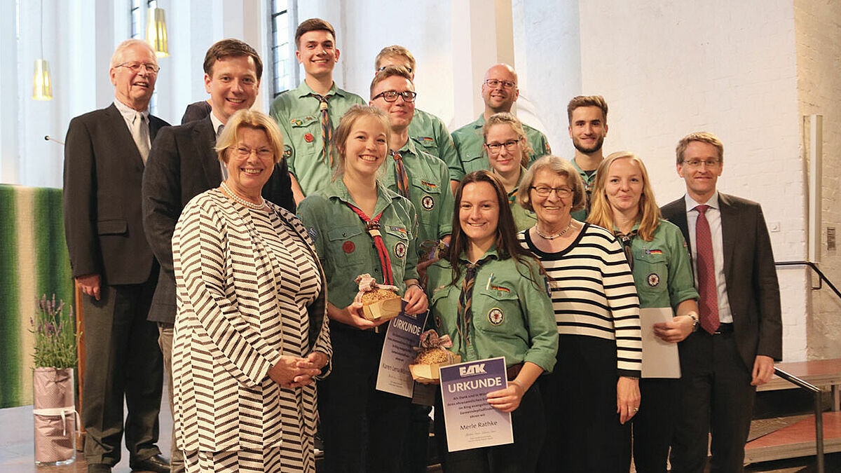 Die geehrten Pfadfinderinnen und Pfadfinder des Rings Evangelischer Gemeindepfadfinder (REGP) inmitten des Evangelischen Arbeitskreises (EAK) der CDU Schleswig-Holstein, Ministerpräsident Daniel Günther (r.) sowie Ulrike Hillmann, Präses der Landessynode der Nordkirche (l.)