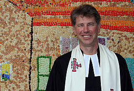 Pastor Rainer Chinnow vor dem Mosaik, das die Gemeinde zum 100.Geburtstag der Friesenkapelle in Wenningstedt geklebt hat