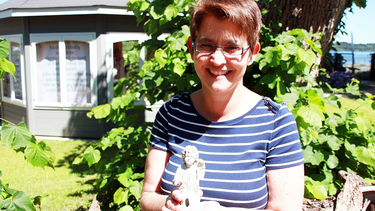 Landesgartenschaupastorin Claudia Süssenbach im "Garten am frischen Wasser" in Eutin. Der Engel in ihren Händen wurde bei Bauarbeiten auf dem Gelände ausgegraben und hat nun einen Platz im Kirchengarten bekommen