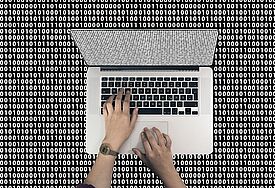 Laptop von oben aufgenommen, auf der Tastaur zwei tippende Hände, drumherum Nullen und Einsen