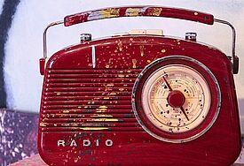 Rotes Baustellenradio, Retro-Design, mit Farbklecksern vollgespritzt