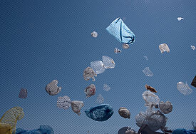 Plastiktüten auf einer Mülldeponie wehen im Wind.