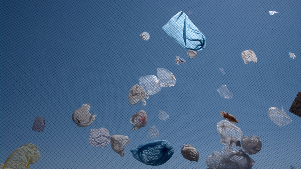 Plastiktüten auf einer Mülldeponie wehen im Wind.